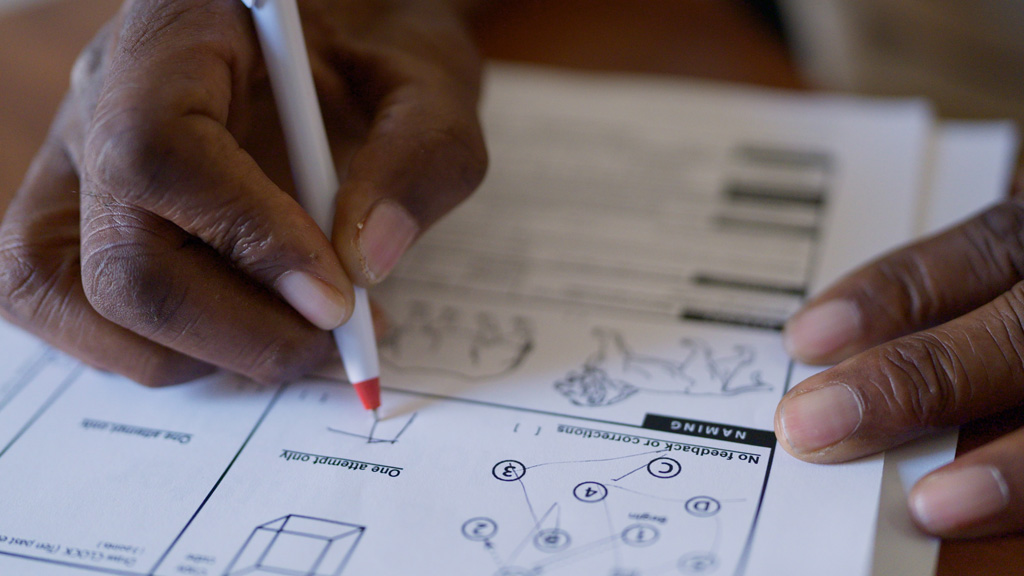 Alzheimer's patient completes written dementia screening with pen.