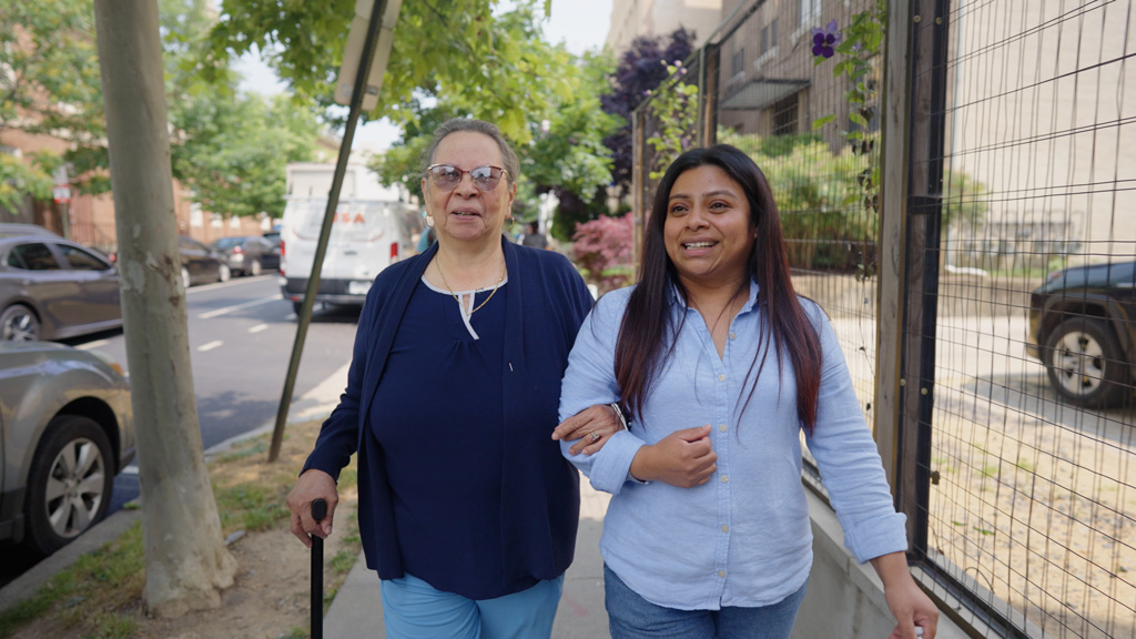 Two women walk together, arm in arm.