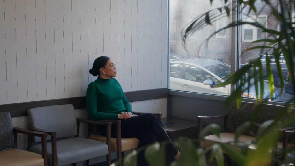 Woman sits waiting in clinic waiting room.