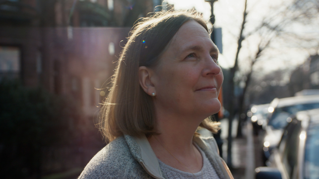 Dr. Shannon Scott-Vernaglia walks, looking happy, outside in Boston, Massachusetts.